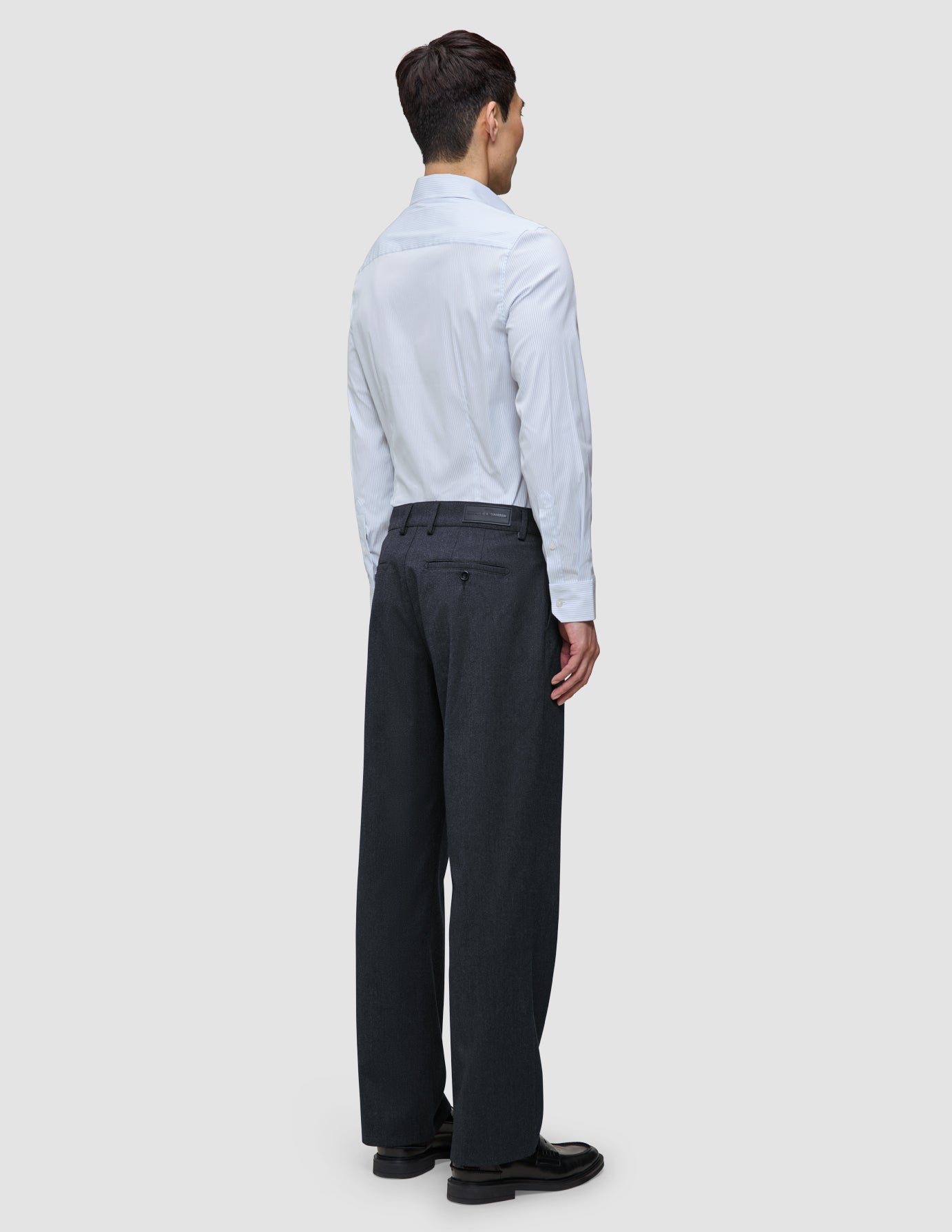 En mann sett bakfra, iført en Elevated Shirt Slim Classic Blue Striped, som er stappet ned i mørkegrå bukser og svarte loafers.